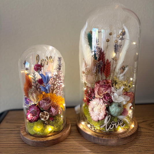 Two decorative glass domes with flowers and 'love' text on a wooden surface.