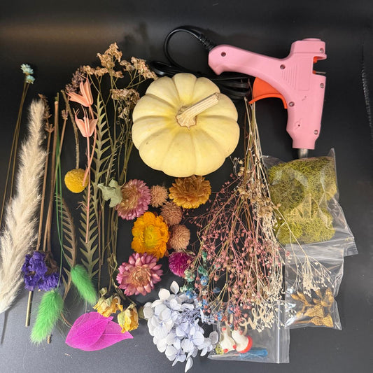 Pink hot glue gun with decorative items on a black background