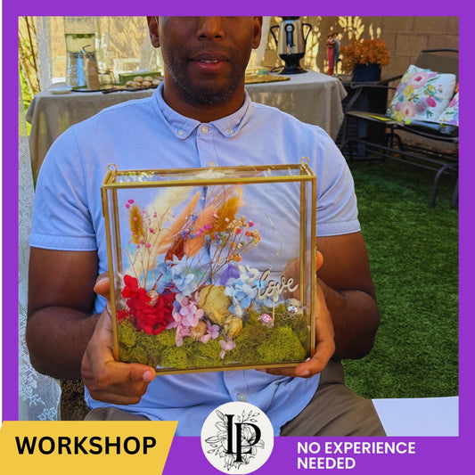 Man holding a decorative box with flowers and 'love' text, outdoors.