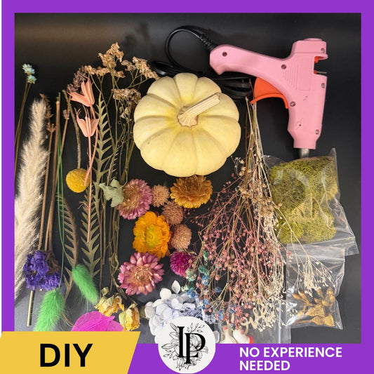 Decorative items including flowers, a pumpkin, and a hot glue gun on a dark surface with a purple border.