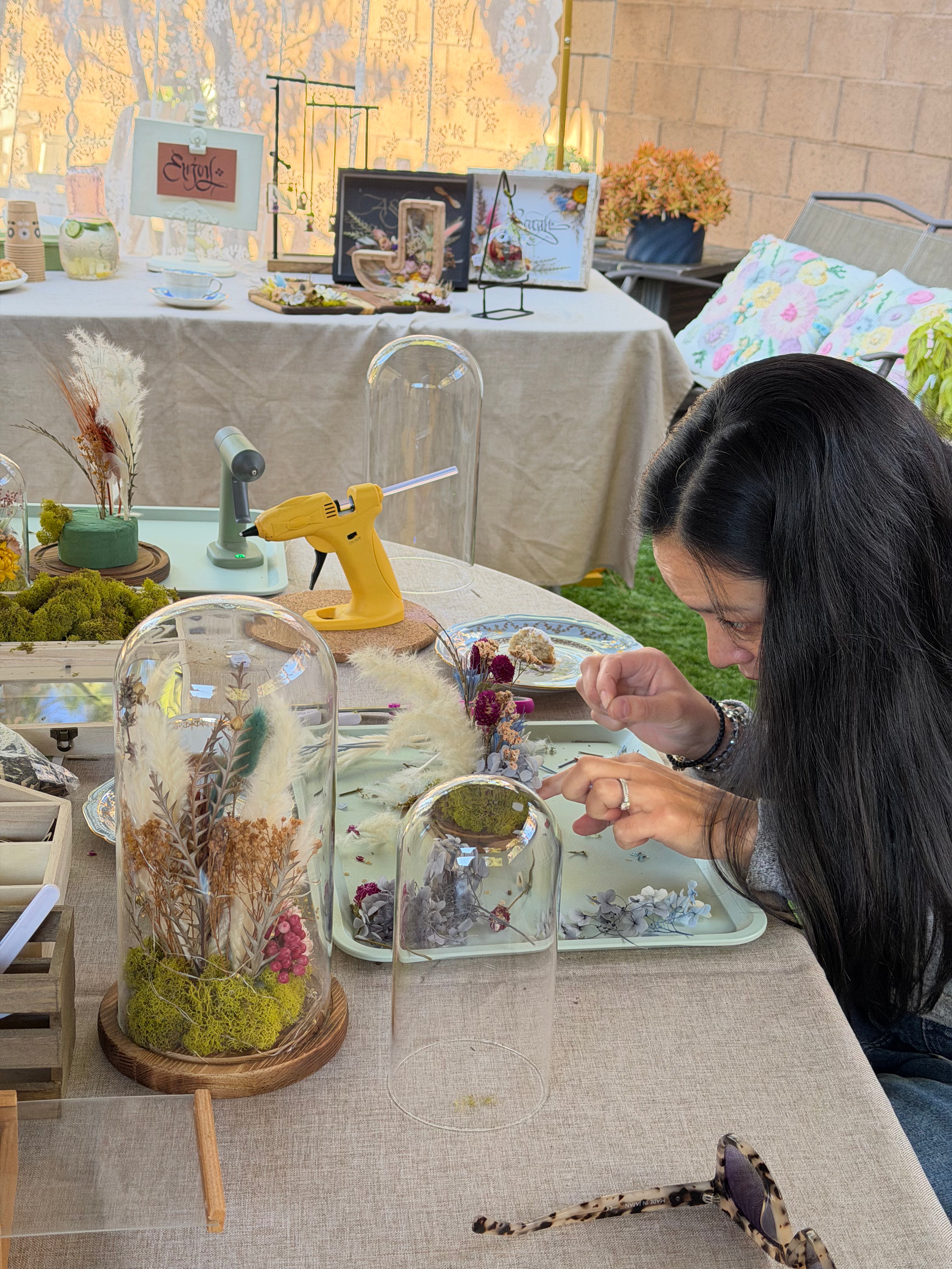 Woman working on a craft project at an outdoor event with tables and decorations.