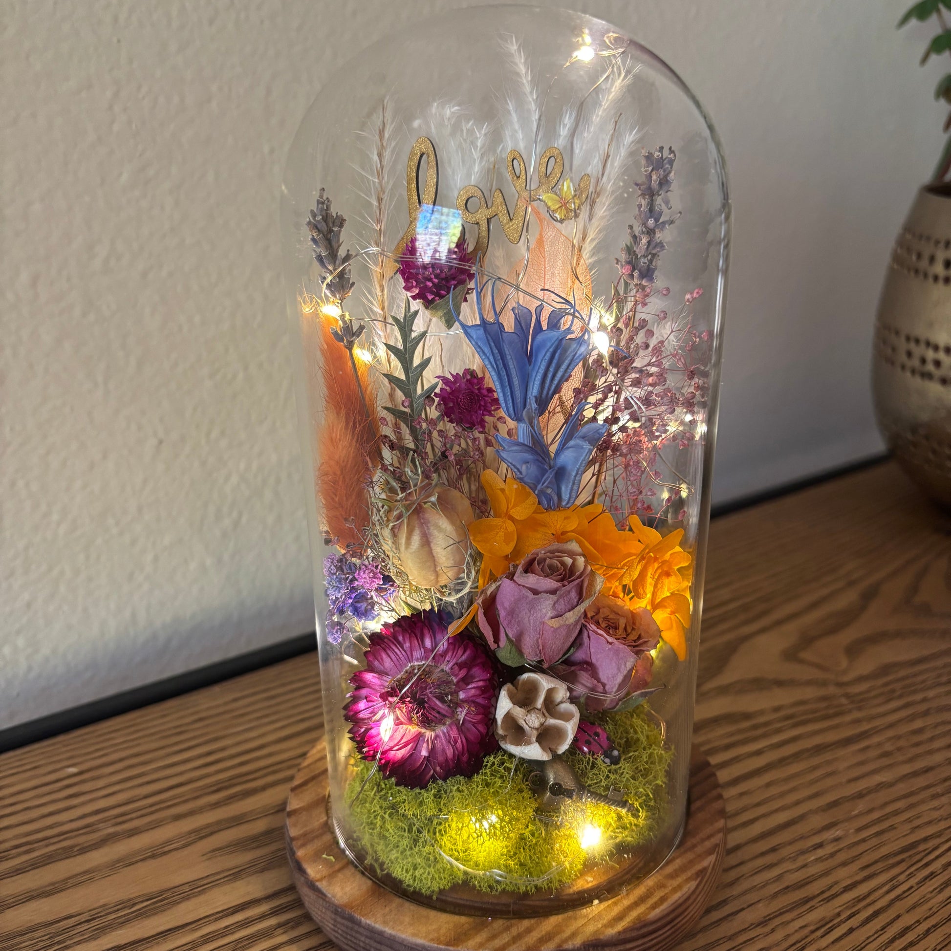 Decorative glass dome with illuminated flowers on a wooden base
