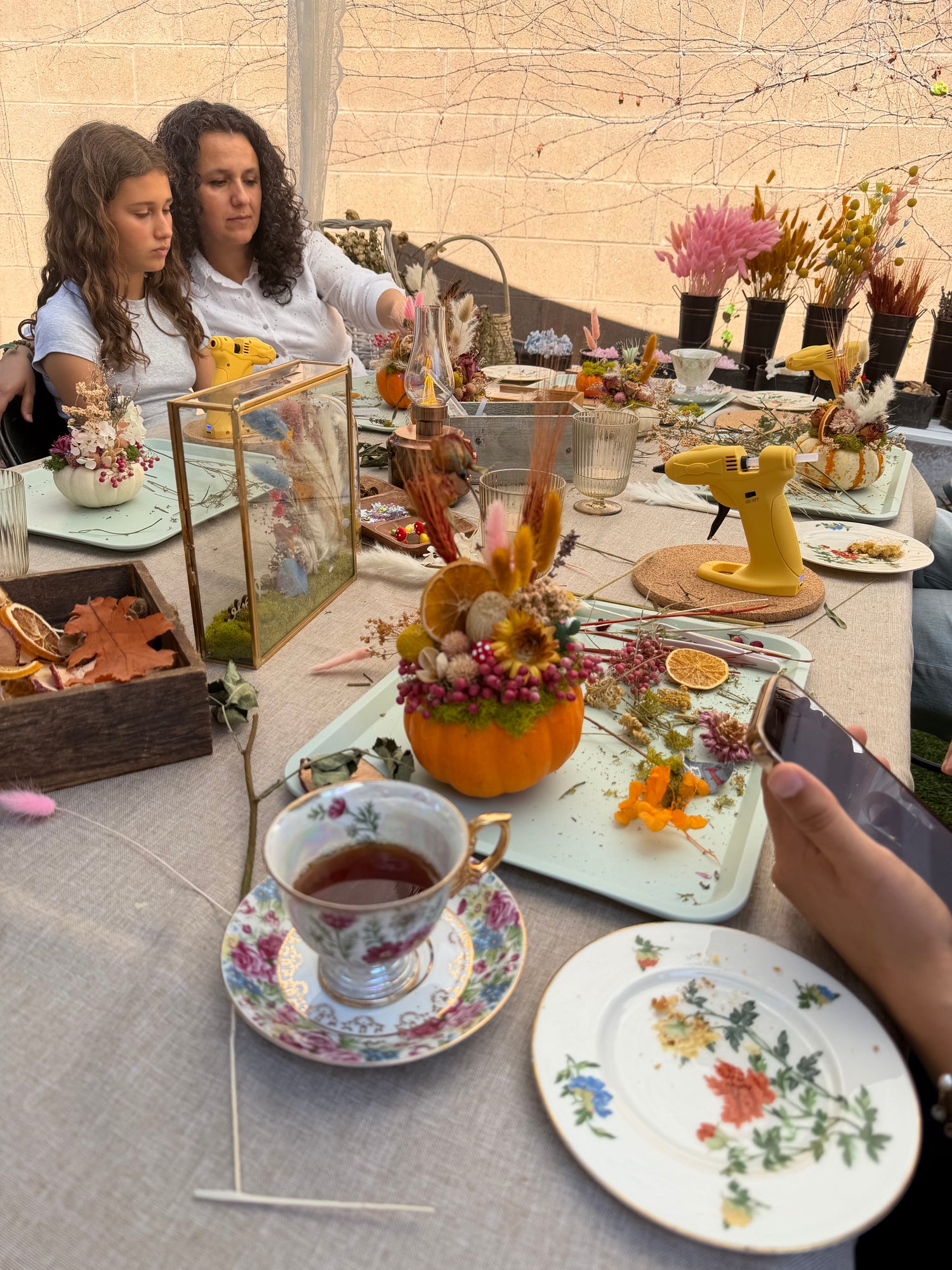 Decorative table setting with floral arrangements and a teacup, viewed from above.