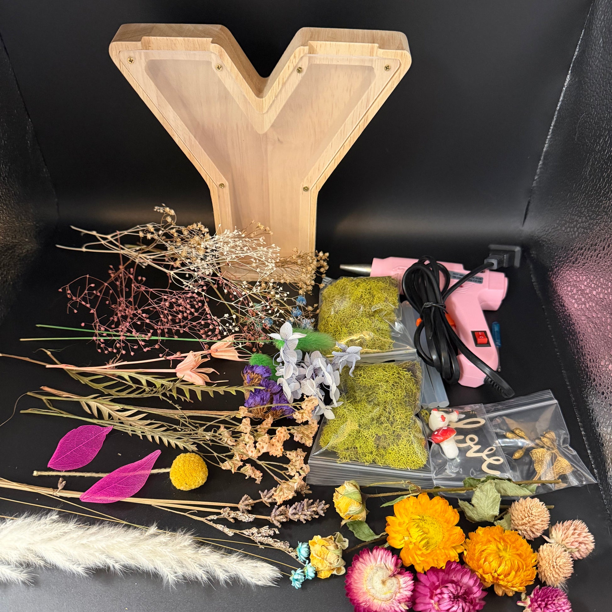 Assorted dried flowers and a wooden board on a black surface